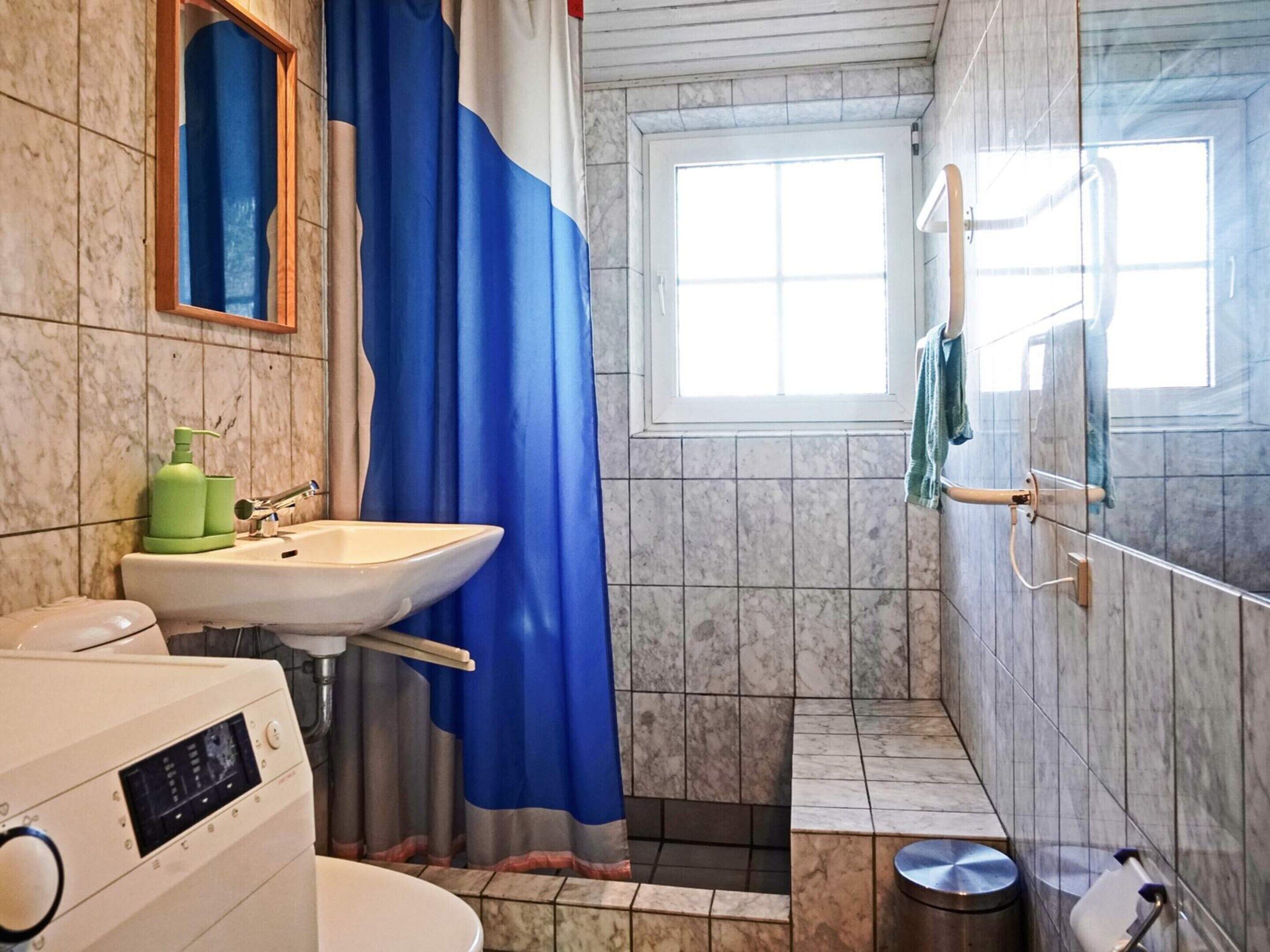 Un baño con lavamanos, espejo, cortina de ducha y ventana.