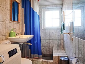 A bathroom with a sink, mirror, shower curtain, and a window. - 4 Person Holiday Home in Allinge (Allinge)