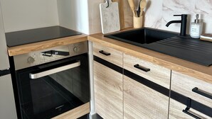 Cocina moderna con armarios de madera, encimera negra, horno integrado y salpicadero de mármol.