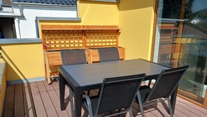A deck with a table and chairs, a wooden fence, and a yellow wall. - Vacation home in Eschweiler - relaxation near the Eifel (Eschweiler)