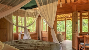 A wooden room with a bed, a desk, and large windows. - Luxury retreat resort in Natural Harmony in Pemuteran! (bali)