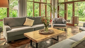 A spacious room with large windows, a ceiling fan, and a variety of seating including a sofa and chairs. - Luxury retreat resort in Natural Harmony in Pemuteran! (bali)