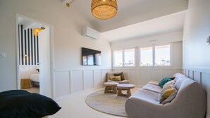 En moderne stue med en sofa, to runde borde og et stort vindue med udsigt.