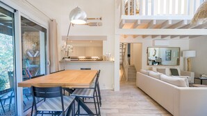 A spacious living area with a wooden dining table, black chairs, a white sofa, and a staircase leading to an upper level. - Villa familiale climatisée avec Piscine (Pyla-sur-Mer)