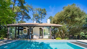 A modern house with a swimming pool, large windows, and a covered patio area. - Villa familiale climatisée avec Piscine (Pyla-sur-Mer)