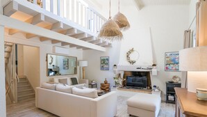 A spacious living room with a white sofa, a fireplace, and a staircase leading to an upper level. - Villa familiale climatisée avec Piscine (Pyla-sur-Mer)