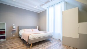 Ein Schlafzimmer mit Bett, Kleiderschrank, Nachttisch, Lampe und Bücherregal.