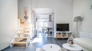 Ein modernes Wohnzimmer mit Treppe, Essbereich und Fernseher.