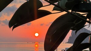 Atardecer sobre un mar tranquilo con barcos y un muelle.