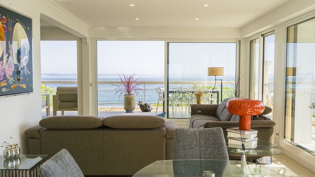 A modern living room with a glass table, a sofa, and a view of the sea. - Appartement 145m², Vue Mer, Parking, Accès Plage (Arcachon)