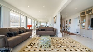 A spacious living room with two sofas, a glass coffee table, and a patterned rug. - Appartement 145m², Vue Mer, Parking, Accès Plage (Arcachon)