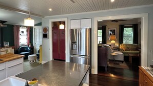 A modern kitchen with stainless steel appliances, a central island, and a dining area with a sofa and table. - In Town Delight! (Manchester)