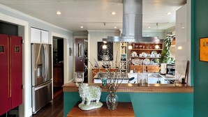 A modern kitchen with stainless steel appliances, a wooden island, and a decorative sheep figurine. - In Town Delight! (Manchester)