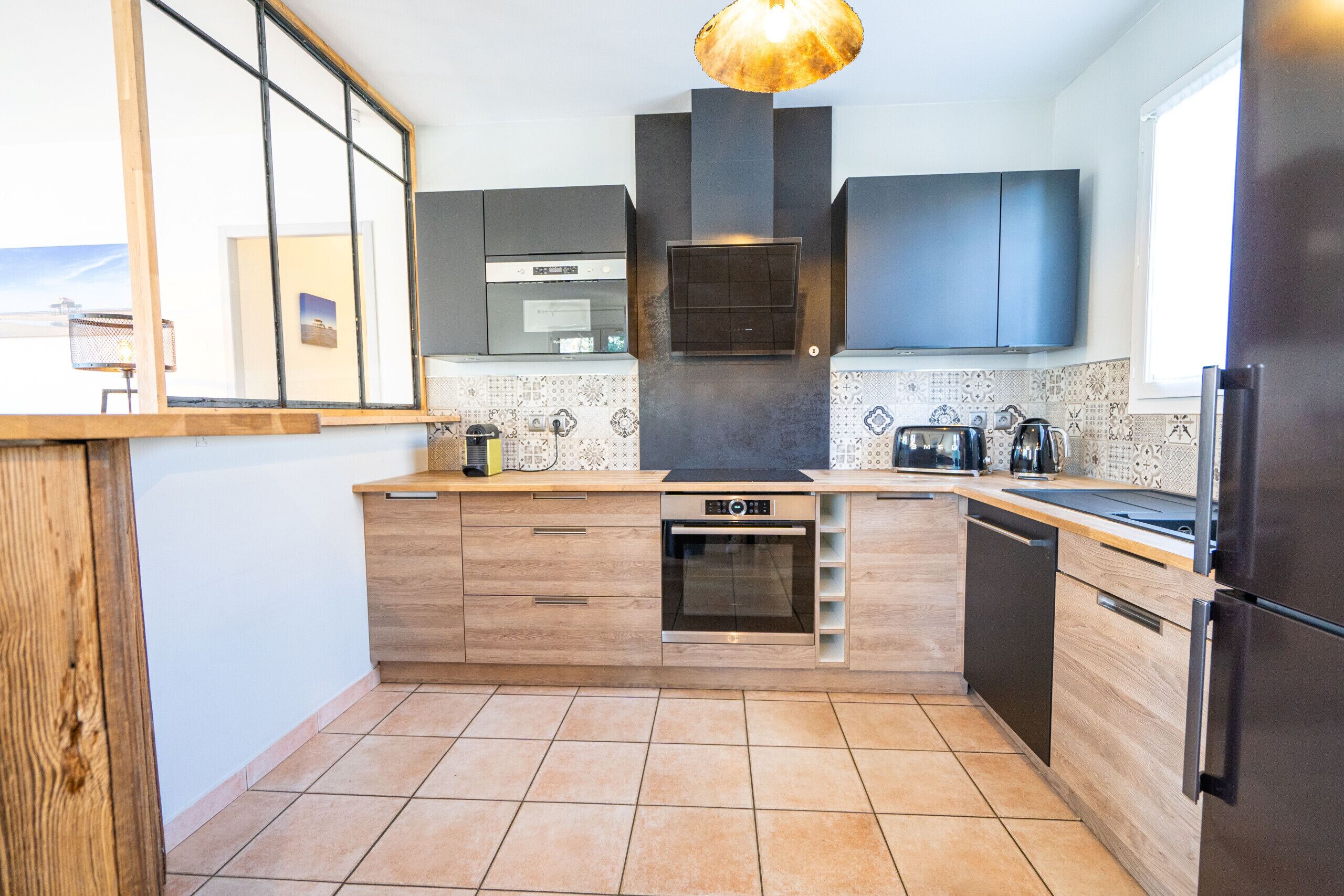 Een moderne keuken met houten kastjes, een inbouwoven, een vaatwasser en een roestvrijstalen koelkast.