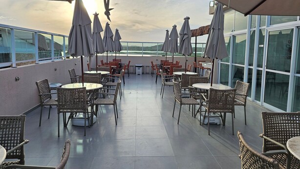 A rooftop terrace with outdoor seating, including wicker chairs and tables, and umbrellas providing shade. - Eco Mirage Residence (Ipojuca)