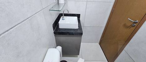 Et lille badeværelse med toilet, vask med sort bordplade og en trædør.