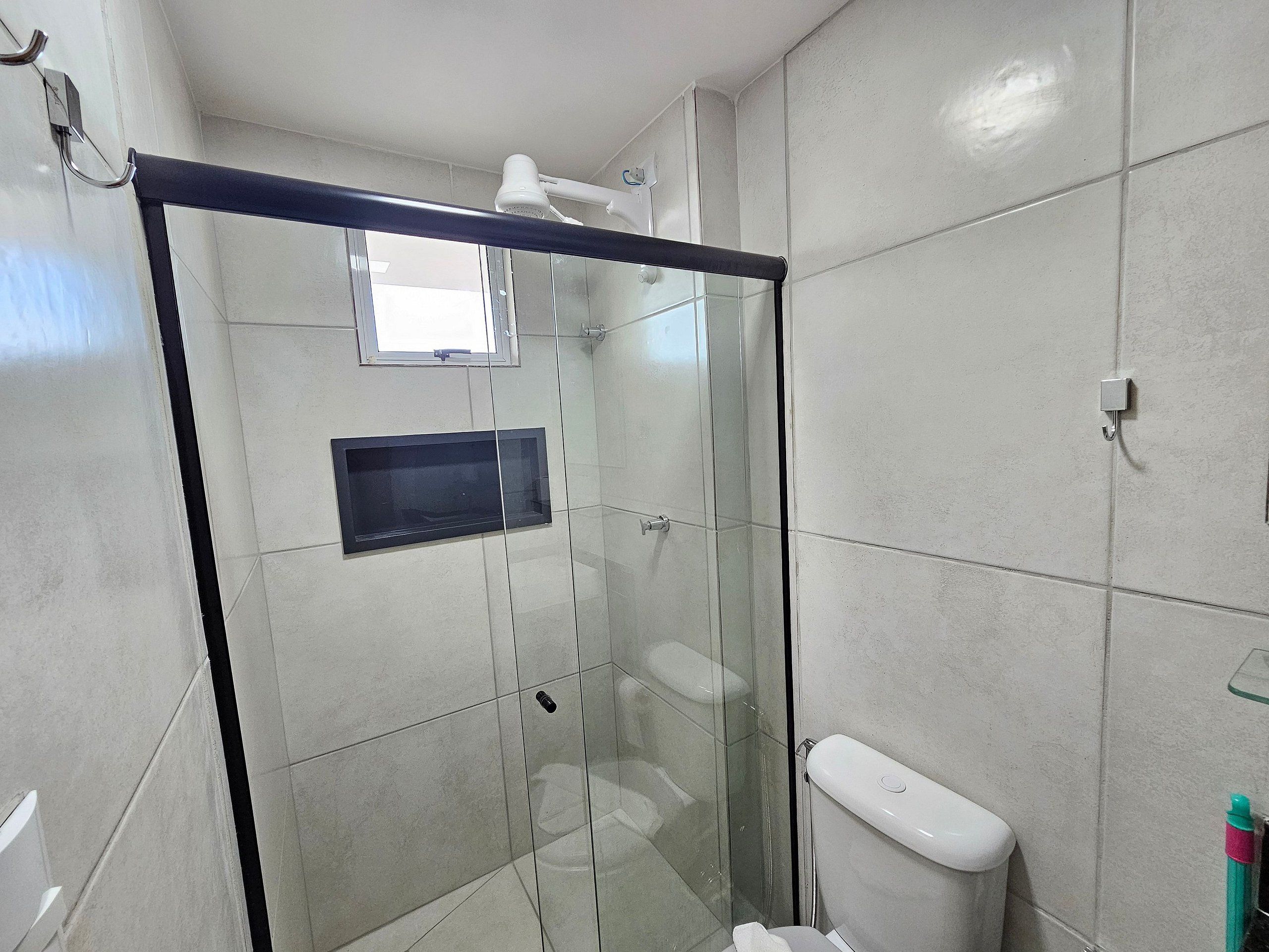 Een moderne badkamer met een douche met glazen wand, toilet en een ingebouwde medicijnkast.