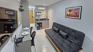 A compact living space with a kitchenette, a dining area, and a sofa. - Eco Mirage Residence (Ipojuca)