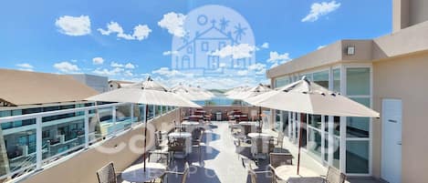 A rooftop terrace with outdoor seating, a pool, and a clear view of the sky.