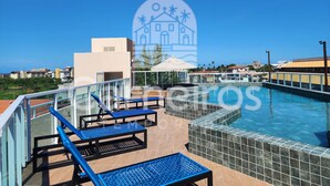 A rooftop pool area with lounge chairs, a tiled pool, and a view of the cityscape. - Eco Mirage Residence (Ipojuca)