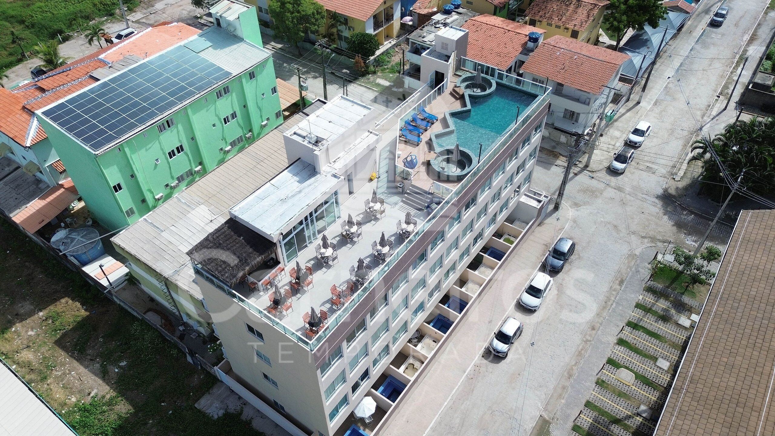 Un edificio de varios pisos con piscina en la azotea y paneles solares.