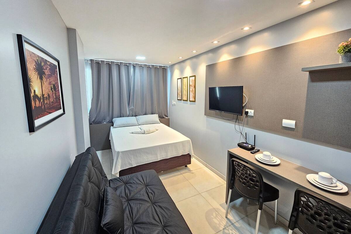 Ein modernes Hotelzimmer mit Bett, Schreibtisch, Fernseher und einer Couch.