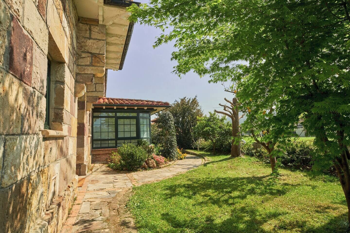 Een stenen gebouw met een overdekte veranda en een pad ernaartoe.