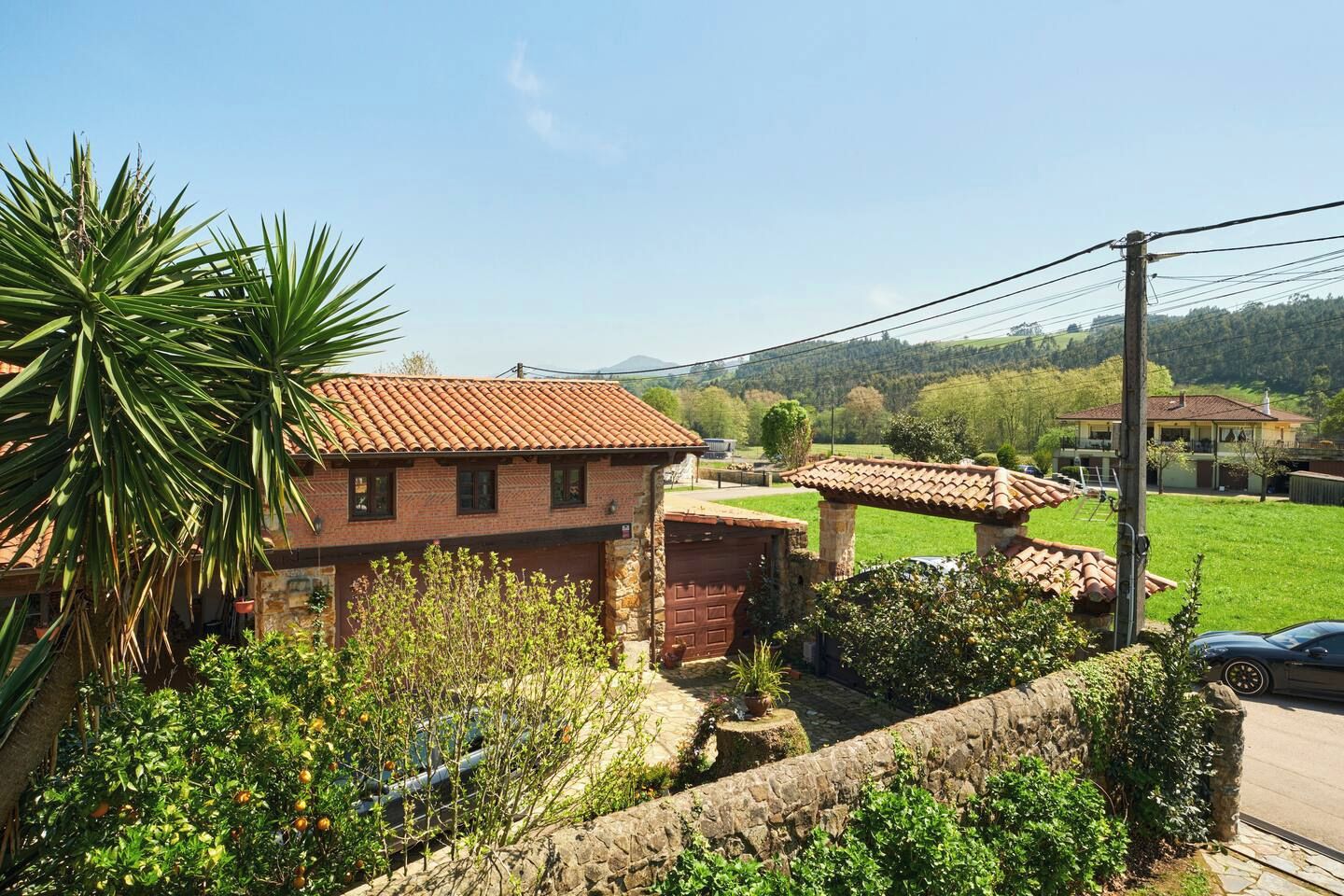 Una propiedad residencial con una casa de ladrillo, un muro de piedra y un jardín.