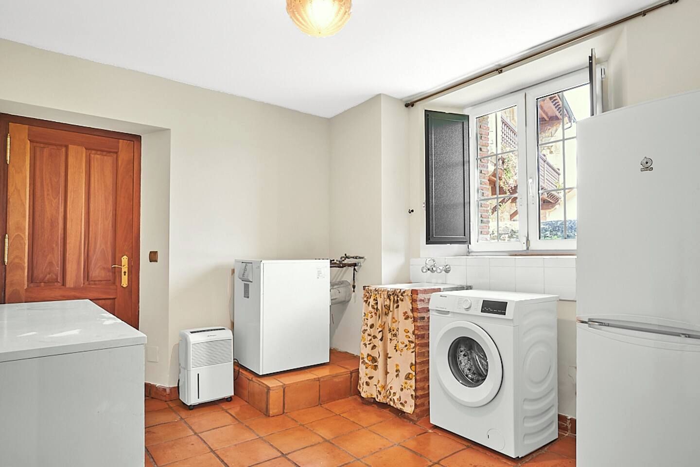 Una cocina compacta con lavadora, un refrigerador pequeño y una puerta.