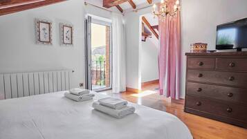 A bedroom with a bed, a dresser, a television, and a view of the outdoors.