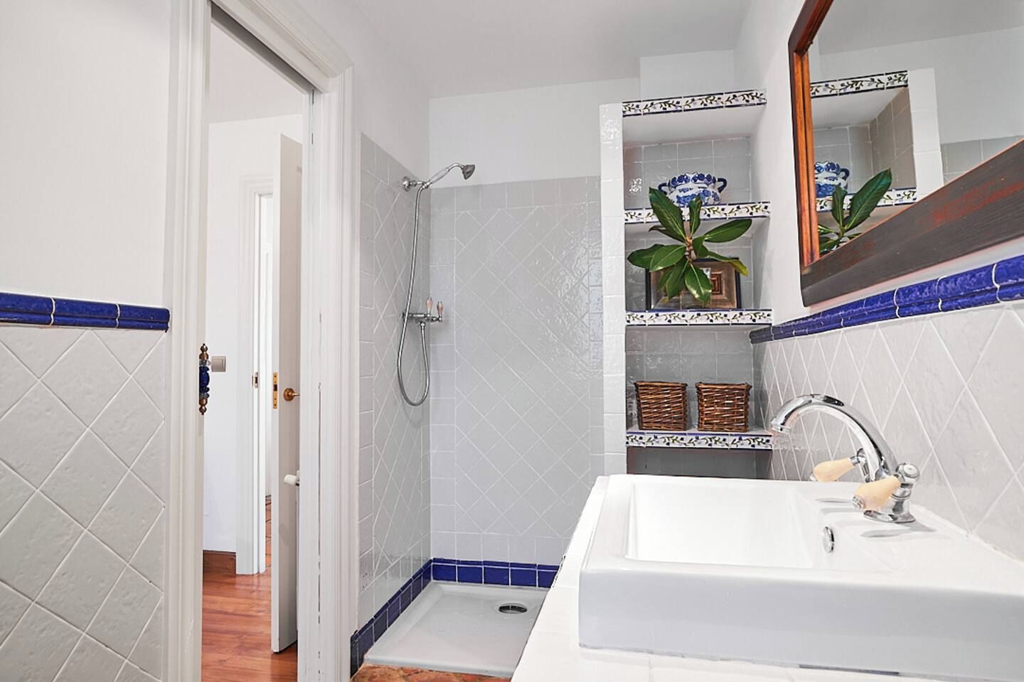 Un bagno con doccia, lavabo e specchio.