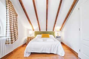 Een slaapkamer met een bed, hoofdeinde, nachtkastje, lamp en een raam met gordijnen.
