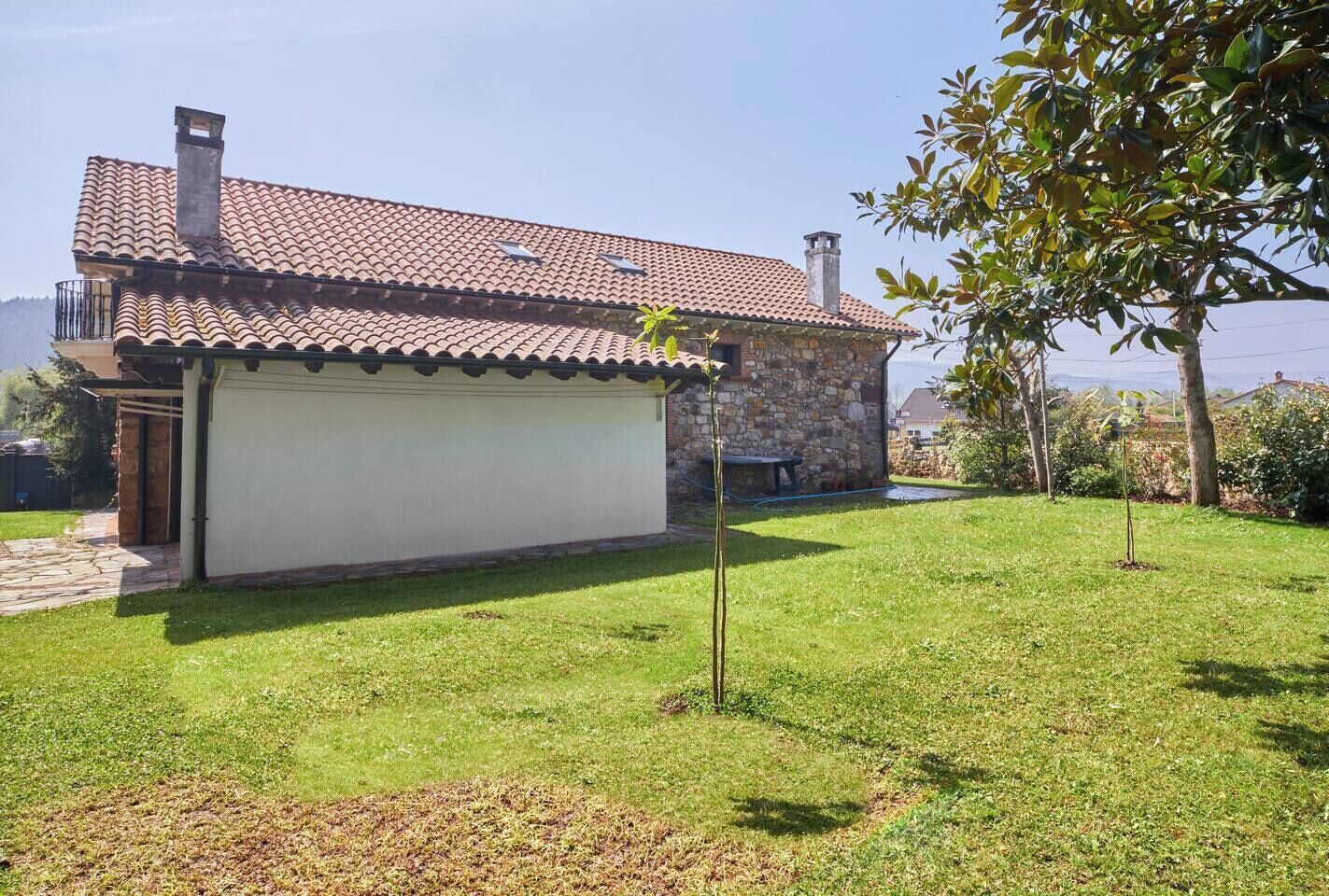 A house with a tiled roof, a stone exterior, and a grassy yard.