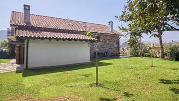 A house with a tiled roof, a stone exterior, and a grassy yard.