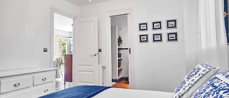 Ein Schlafzimmer mit einem Bett, einem Schminktisch, einer Chandelierleuchtre und einer Tür zu einem Badezimmer.