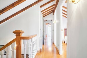 Un escalier en bois, avec des balustrades blanches, menant à l’étage supérieur.
