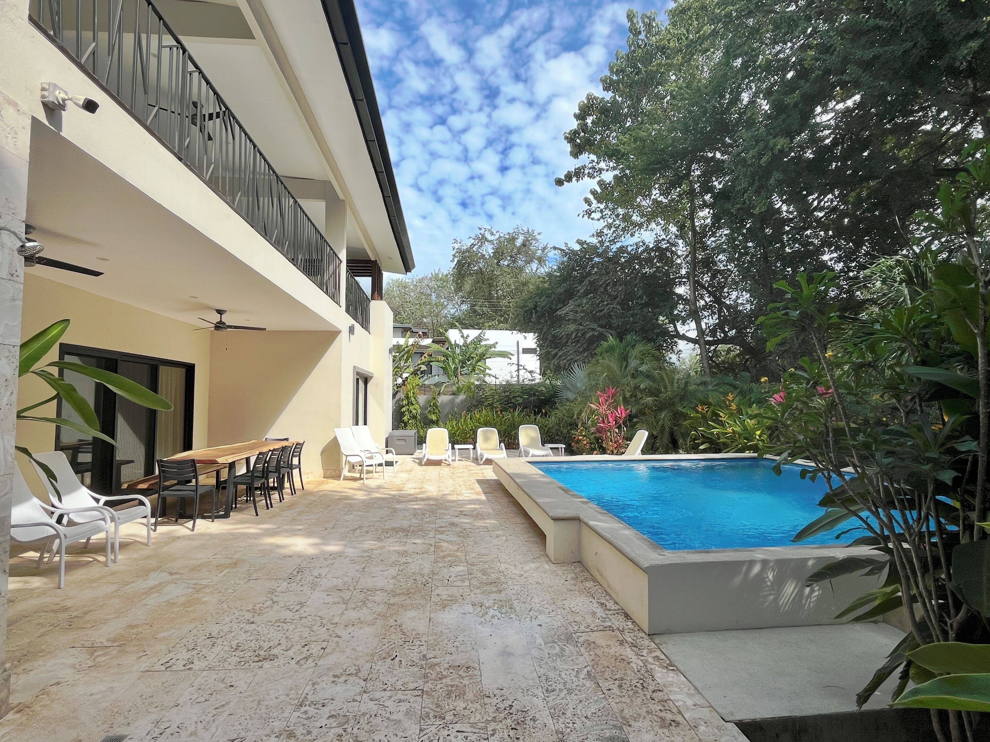 Private outdoor pool, loungers and table for dining surrounded by gardens