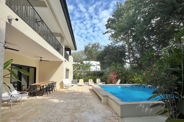 Private outdoor pool, loungers and table for dining surrounded by gardens