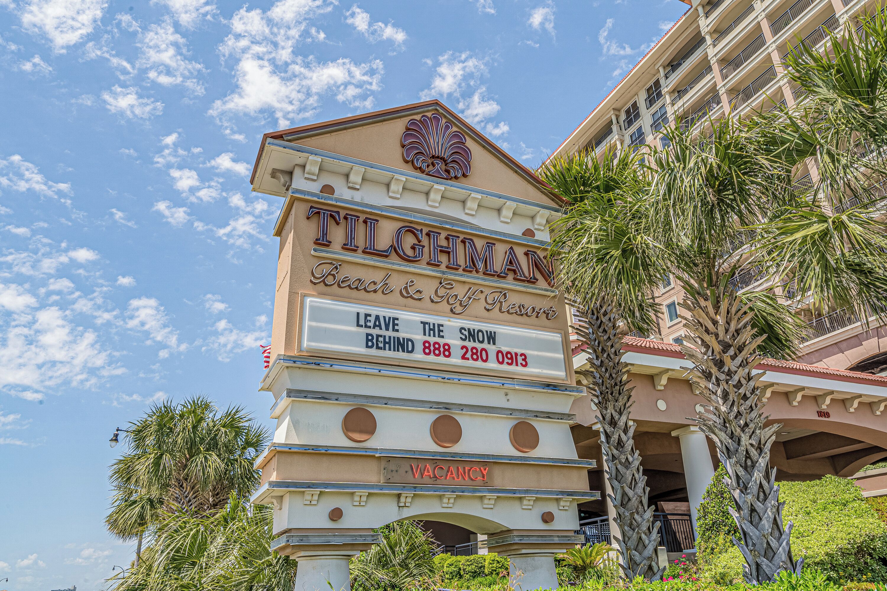 A sign for the 'TILGHMAN Beach & Golf Resort' with a vacancy notice and contact number.