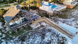 A beachfront property with a pool, wooden deck, and a covered area.