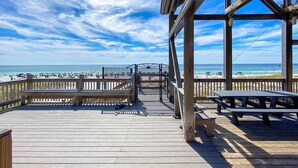 Una terraza de madera con vista a la playa y al océano.