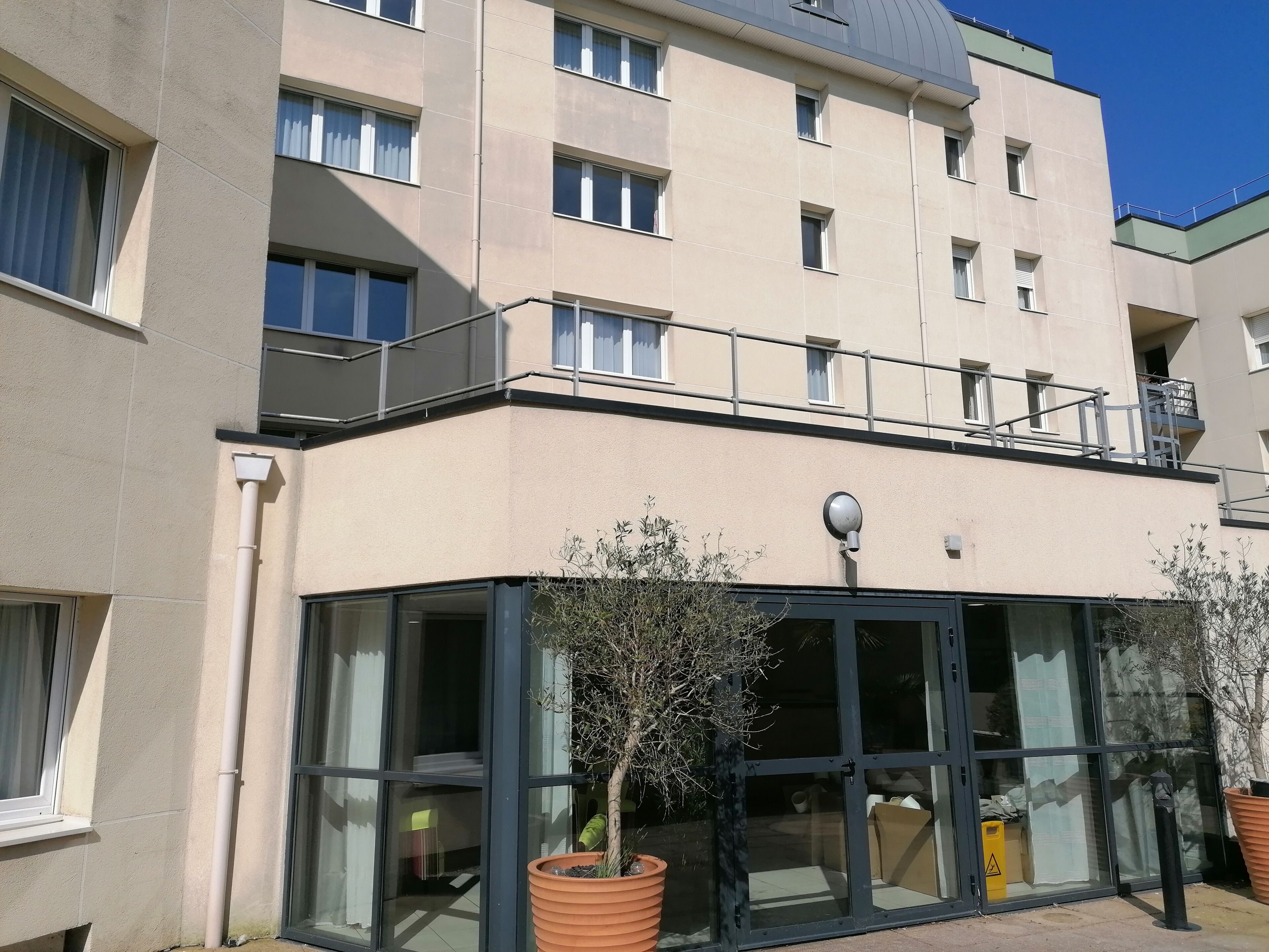 A multi-story building with a flat facade, large windows, and a balcony on the upper floor.