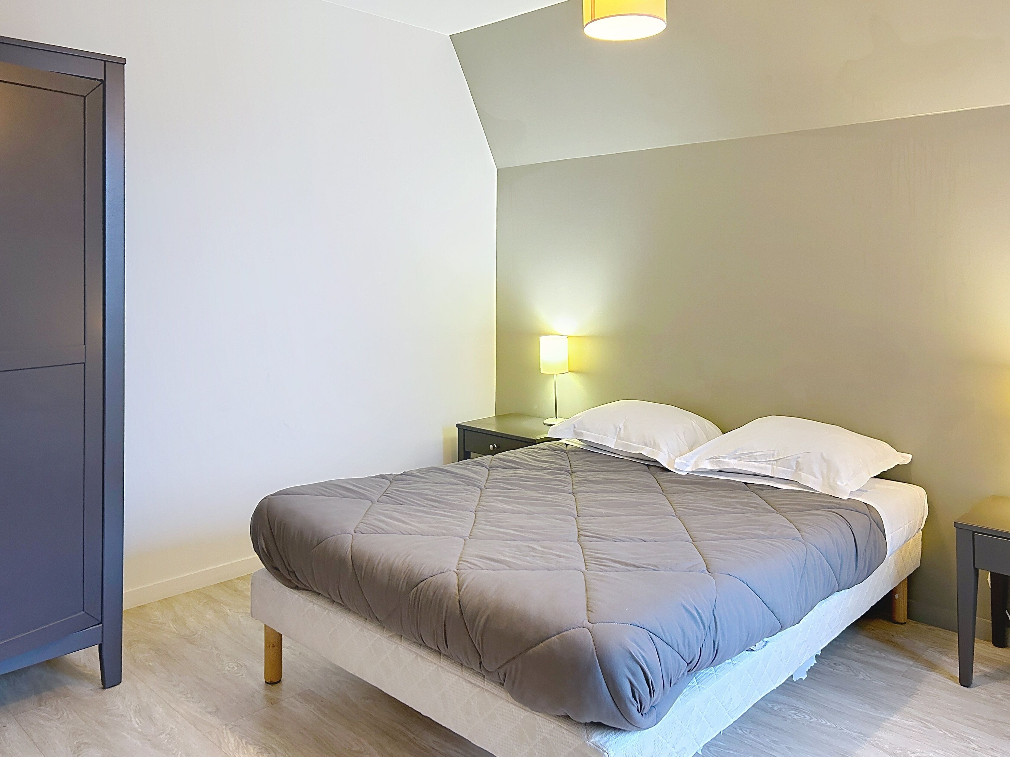 A bedroom with a bed, nightstands, a lamp, and a wardrobe.