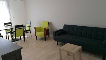 A living room with a dark sofa, a small wooden table, and a green armchair.