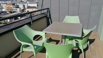 A balcony with a table and two chairs, overlooking a cityscape.