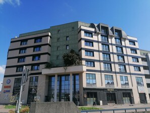 Un edificio de varios pisos con un diseño arquitectónico moderno, con amplias ventanas y fachada verde.