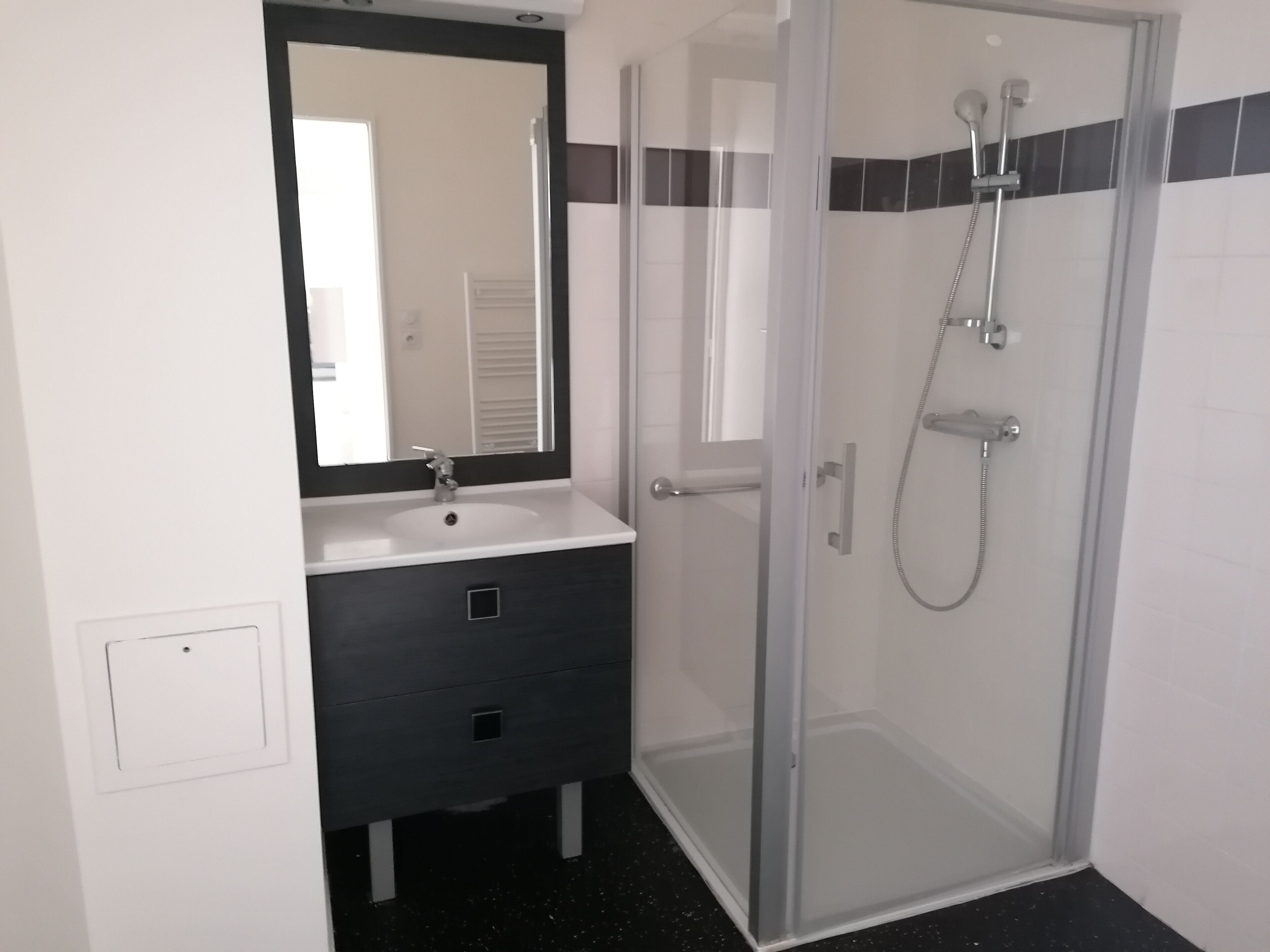 A bathroom with a glass shower enclosure, a white sink, and a dark vanity.