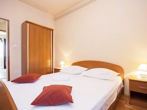Een hotelkamer met een bed, twee nachtkastjes, een kledingkast en een deur.