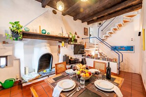 A dining area with a fireplace, a staircase, and a view of the living room. - Antica Torre (Lugano)