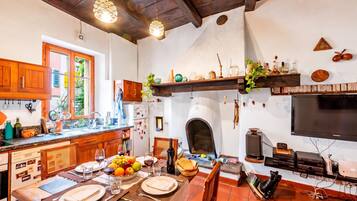A kitchen with a dining area, wooden cabinets, a built-in oven, and a television.